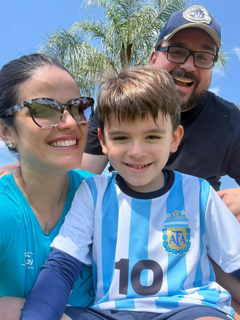 Pais e filho juntos em uma fotografia de família ao ar livre.
